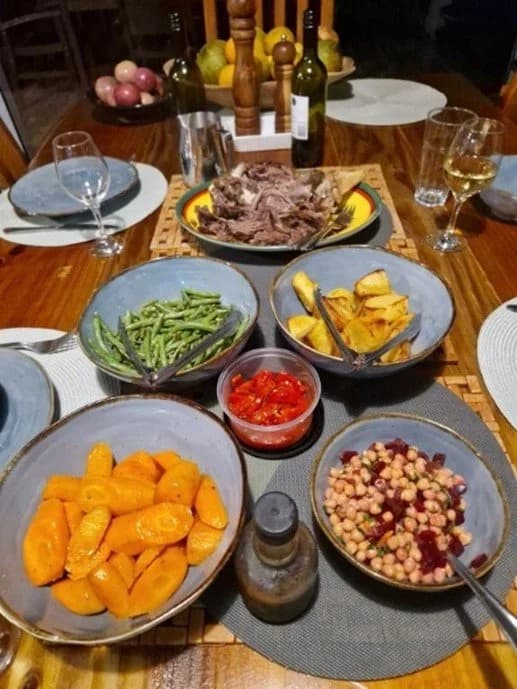 A dinner table spread with bowls of vegetables, meat and fruit