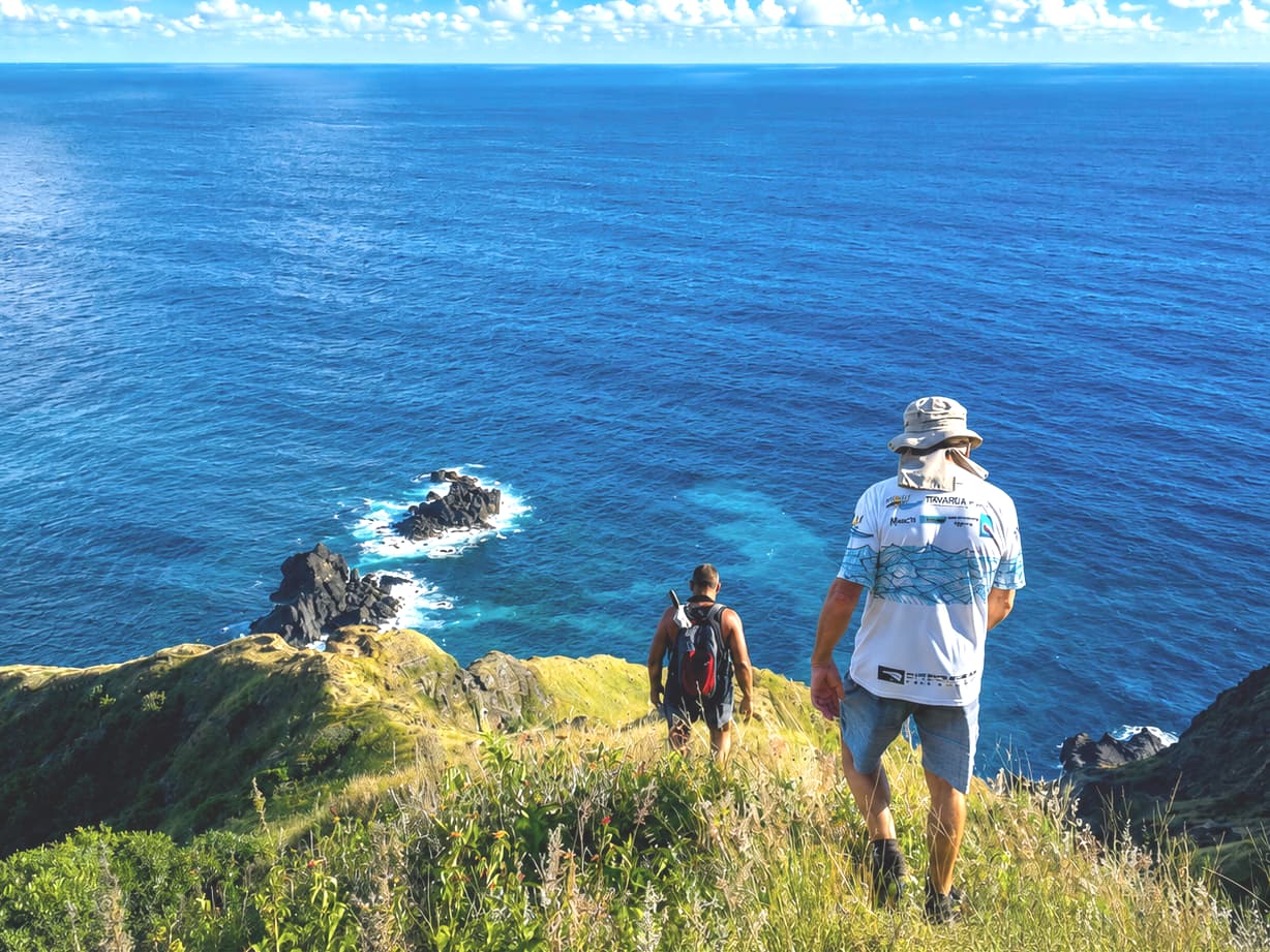 Walkers on a grassy ridge high above the sea