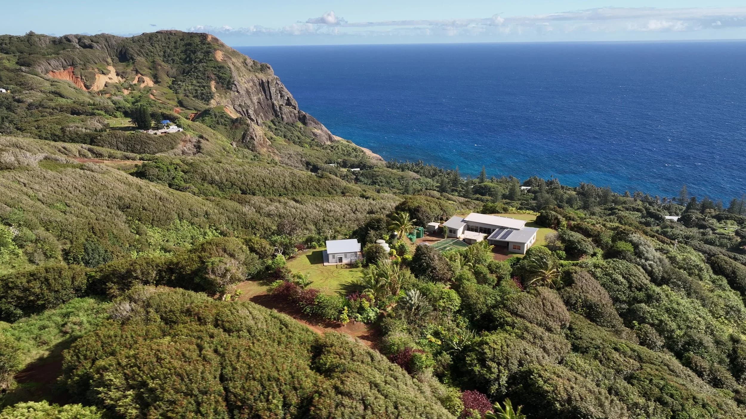 Big Flower and Little Flower from the air, two white buildings among green bush above the sea