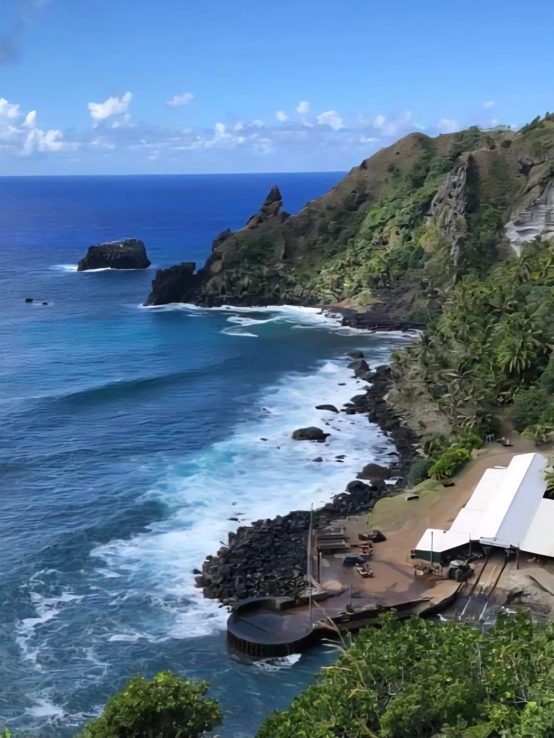 Coastal scene with rocky cliffs, blue ocean waves, a boat dock, and a green hillside under a partly cloudy sky.