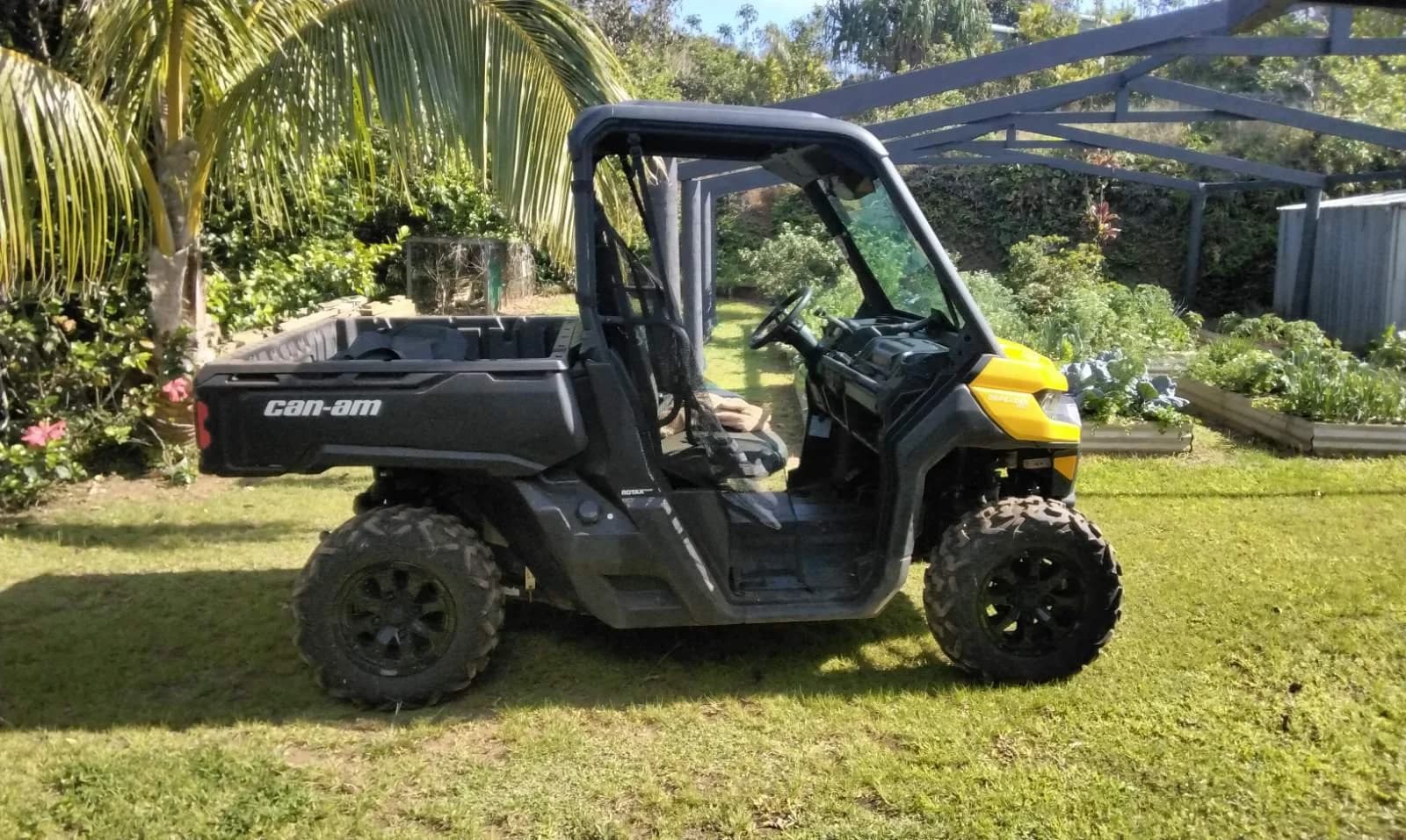A yellow all-terrain vehicle parked on the lawn among the gardens
